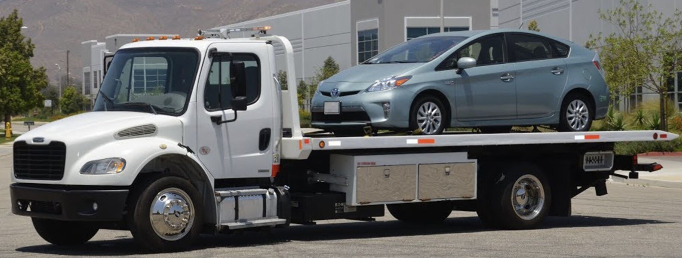 Flatbed tow truck carrying a car in West Babylon, NY